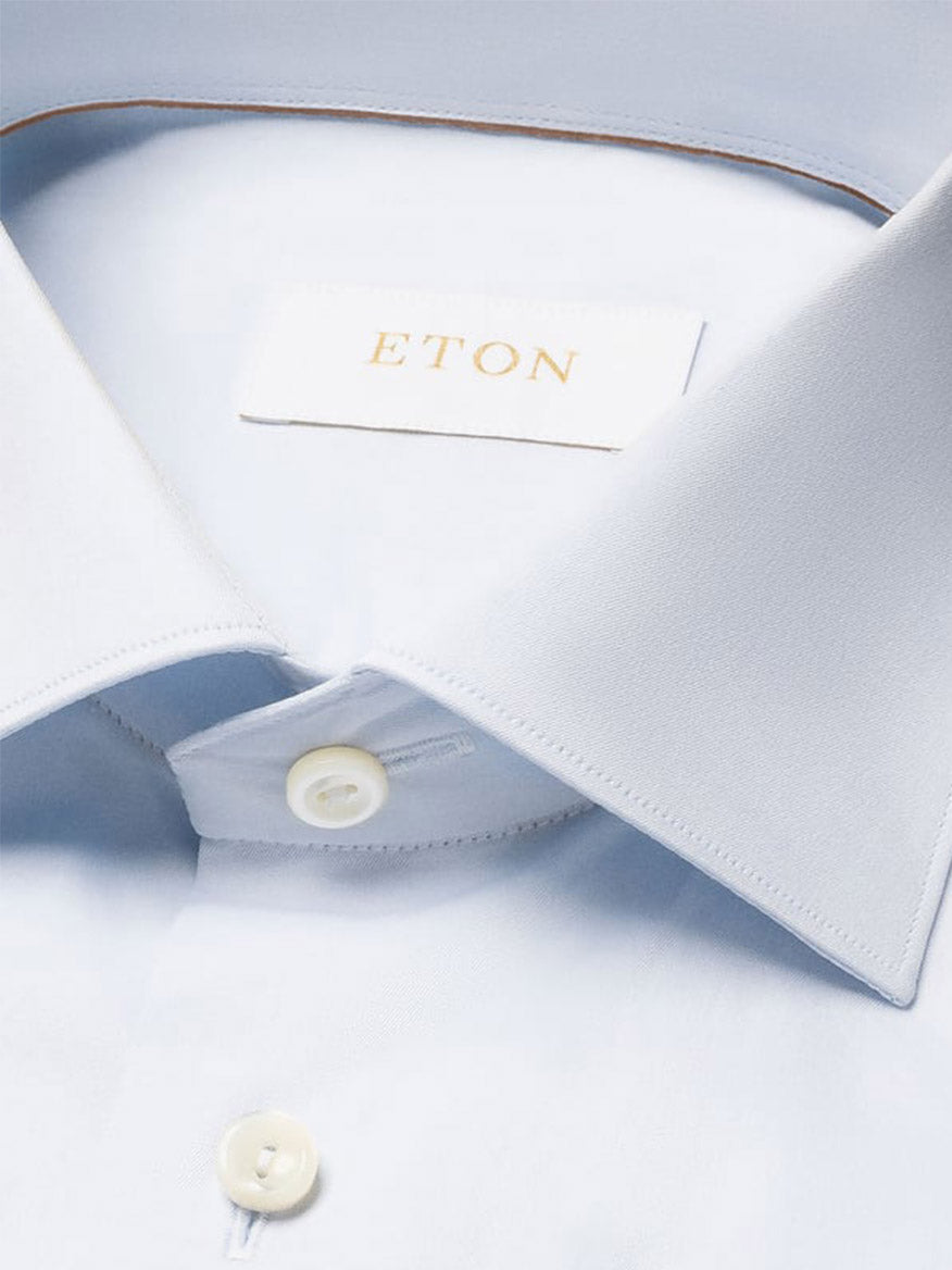 Close-up of the Eton Slim Fit Solid Elevated Twill Dress Shirt in Light Blue, neatly folded, featuring crease-resistant organic Supima cotton, white buttons, and the "ETON" label inside the collar.