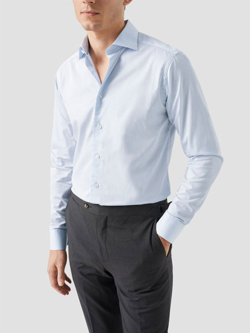 A man wears the Eton Slim Fit Solid Elevated Twill Dress Shirt in light blue with dark gray dress pants, standing against a plain light gray background.