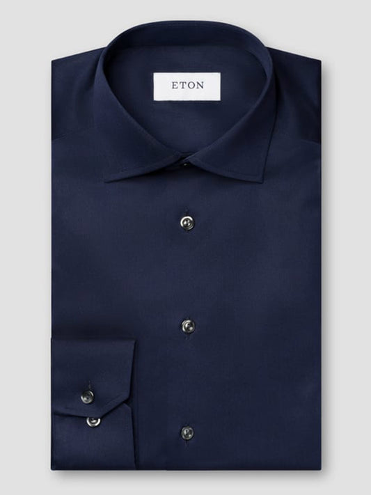 A neatly folded Eton Contemporary Fit Solid Signature Twill Dress Shirt in navy blue with black buttons and an "ETON" label inside the collar, shown against a plain light gray background.