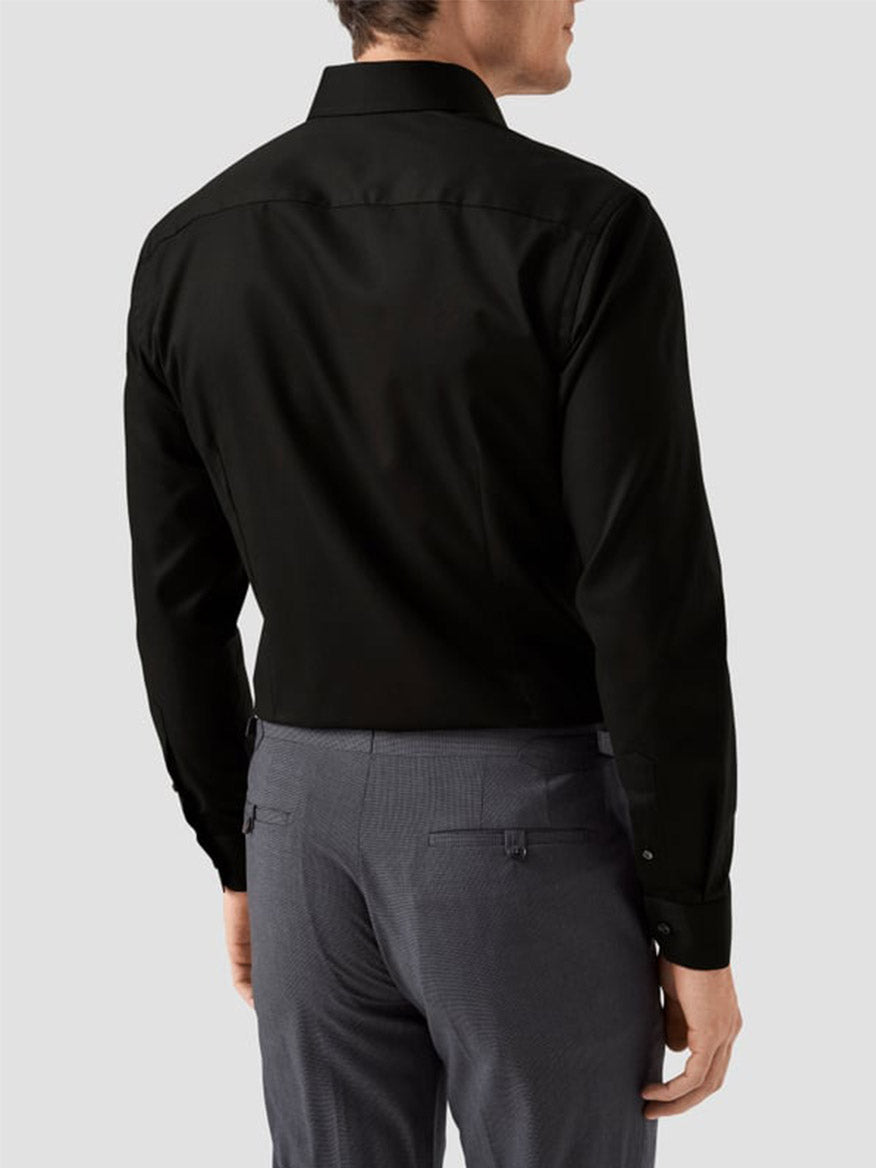 A man is seen from the back wearing an Eton Slim Fit Solid Signature Twill Dress Shirt in black with a cut away collar, paired with gray dress pants, against a light gray background.