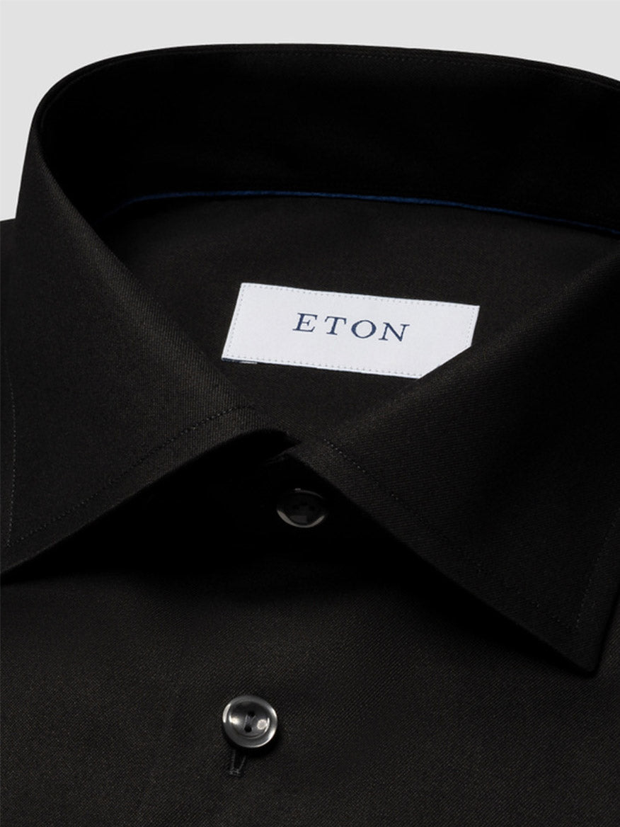 Close-up of the Eton Slim Fit Solid Signature Twill Dress Shirt in Black with a cut away collar, crafted from crease-resistant organic Supima cotton and featuring a white "ETON" label and visible black button.