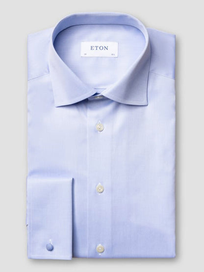 A neatly folded Eton Slim Fit Solid Signature Twill Dress Shirt in light blue with French cuffs, spread collar, and white buttons, featuring the “ETON” label on the inside collar.