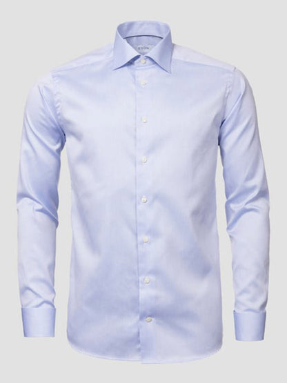 The Eton Slim Fit Solid Signature Twill Dress Shirt in light blue features French cuffs and a collar, crafted from wrinkle-free fabric and displayed against a plain gray background.
