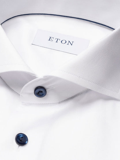 Close-up of an Eton Slim Fit Solid Signature Twill Dress Shirt in white with navy details, featuring an extreme cut away collar and the visible Eton label inside.