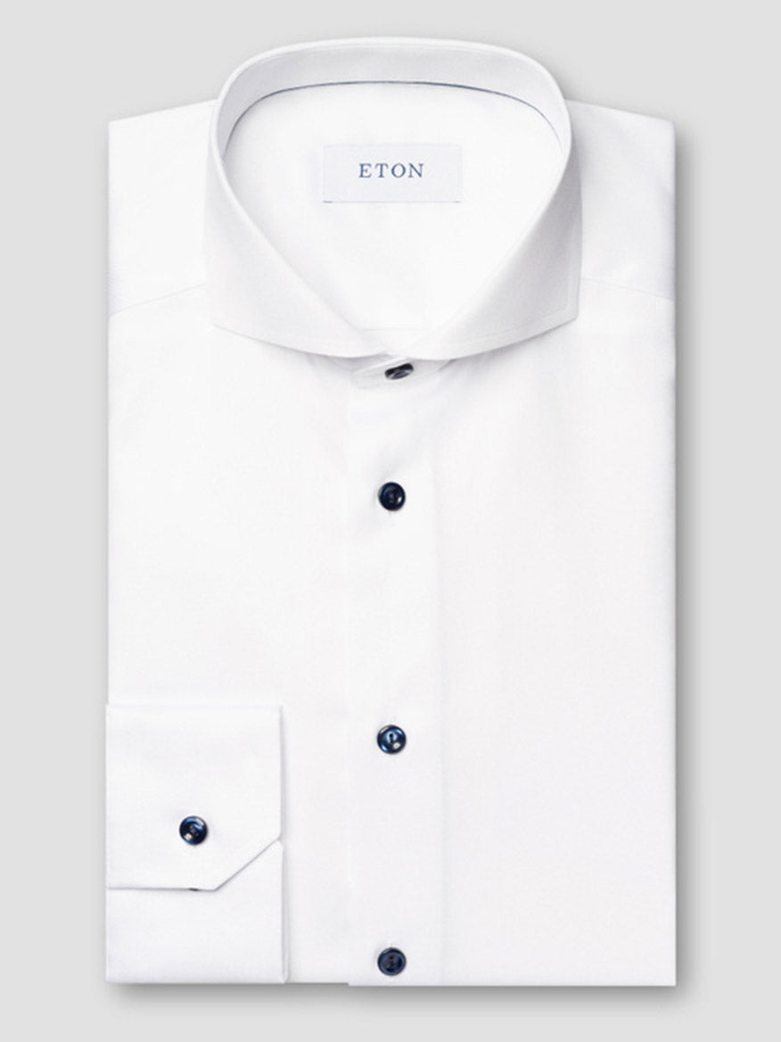 A white Eton Slim Fit Solid Signature Twill Dress Shirt with an extreme cut away collar and navy details, elegantly folded and showing the brand label inside the collar.