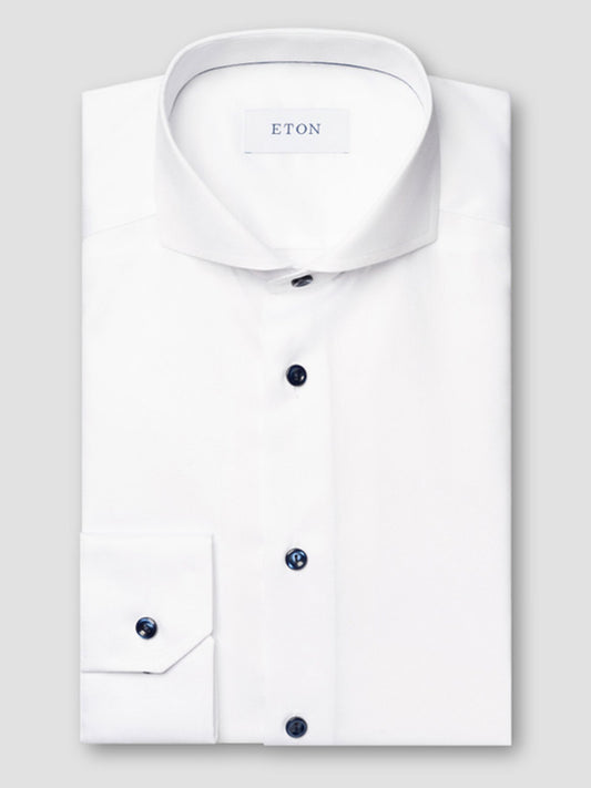 A white Eton Slim Fit Solid Signature Twill Dress Shirt with an extreme cut away collar and navy details, elegantly folded and showing the brand label inside the collar.