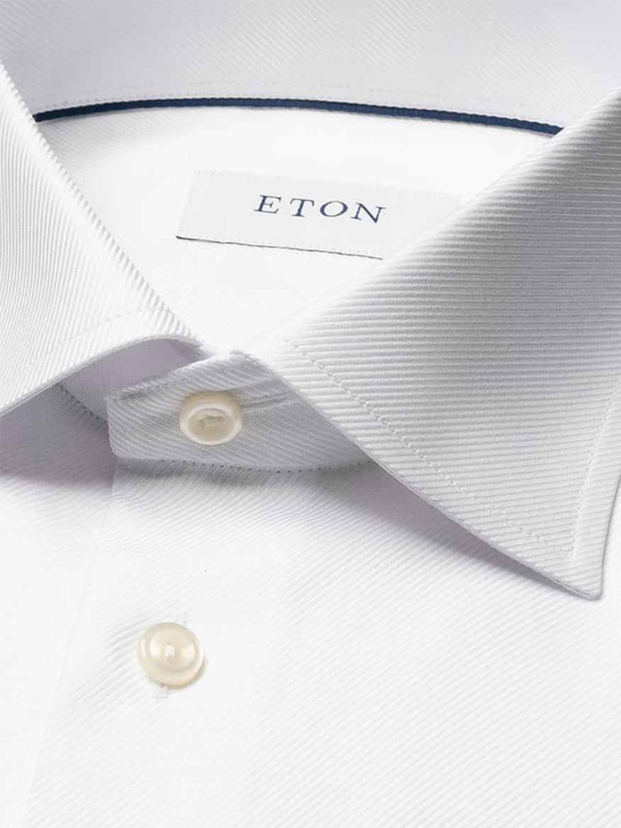 Close-up of an Eton Contemporary Fit Solid Textured Twill Dress Shirt in white, featuring a pointed collar, buttoned placket, single cuff, and inner label with the brand name “ETON.”.