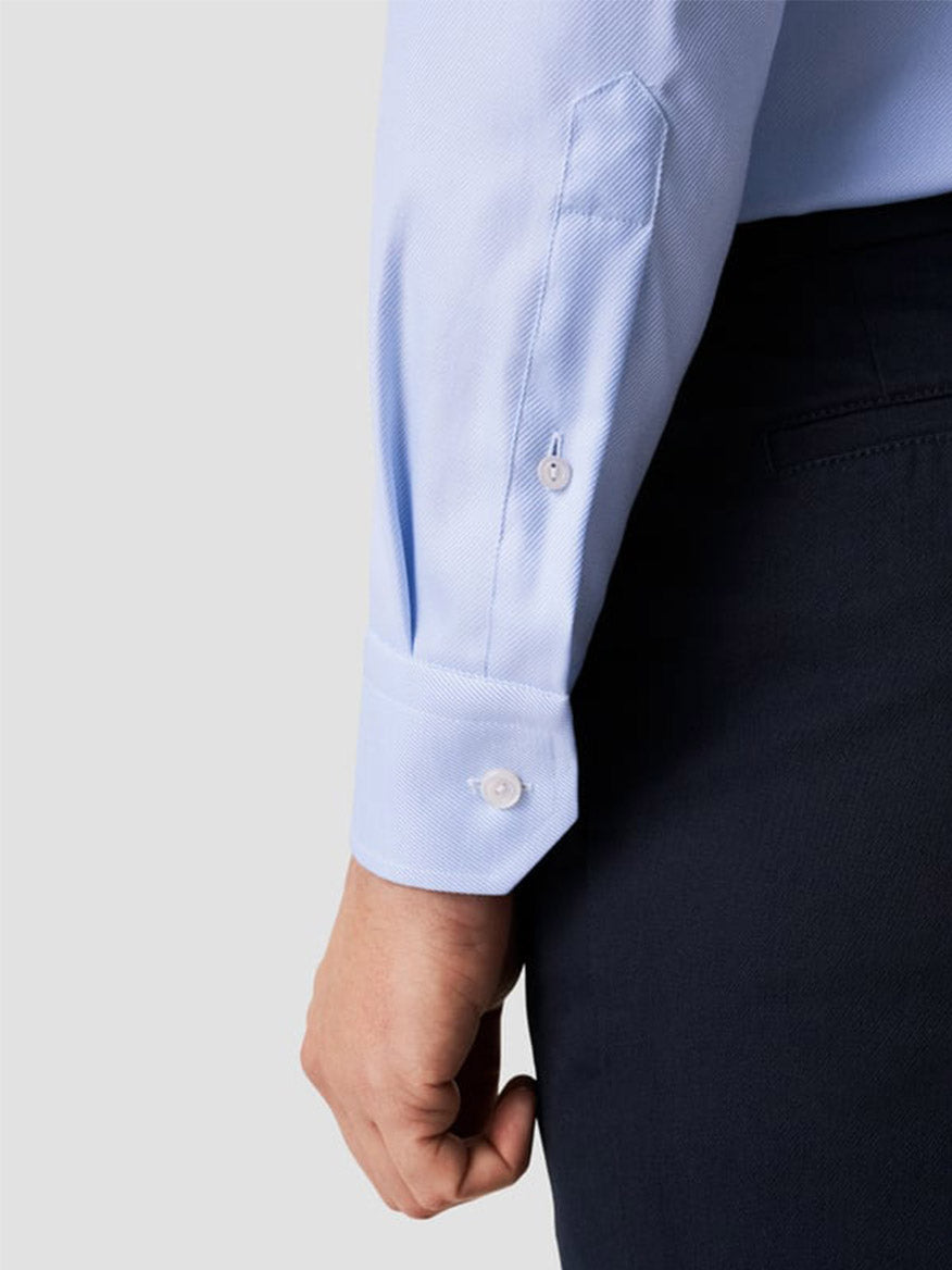 A person shown from the side is wearing the Eton Contemporary Fit Solid Textured Twill Dress Shirt in light blue, paired with dark pants.