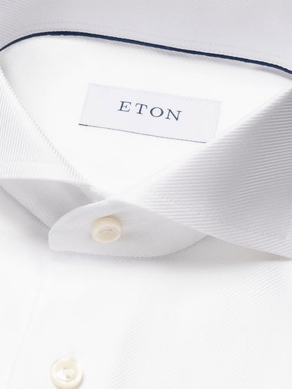 Close-up of the Eton Slim Fit Solid Textured Twill Dress Shirt in White featuring an extreme cut away collar, visible buttons, and an "ETON" label—an ideal choice for business attire.