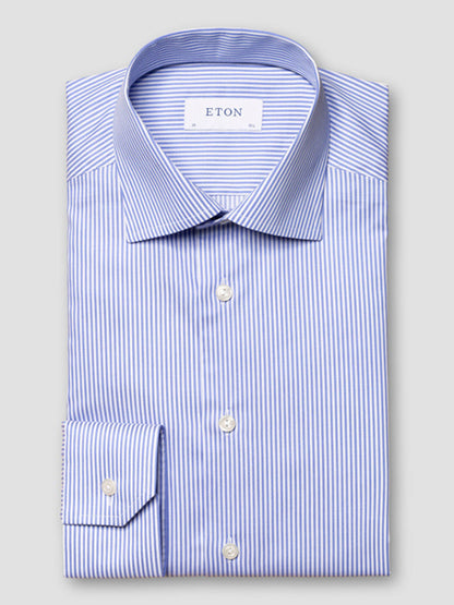 The Eton Contemporary Fit Striped Fine Twill Dress Shirt in Light Blue features blue and white stripes, a classic collar, and button front—perfect for business attire, displayed neatly folded against a plain grey background.