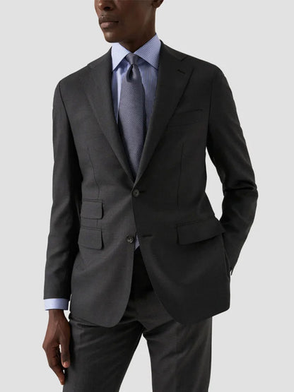 A person in a dark gray suit and an Eton Contemporary Fit Striped Fine Twill Dress Shirt in light blue with a patterned tie, standing with one hand in their pocket against a plain light background.