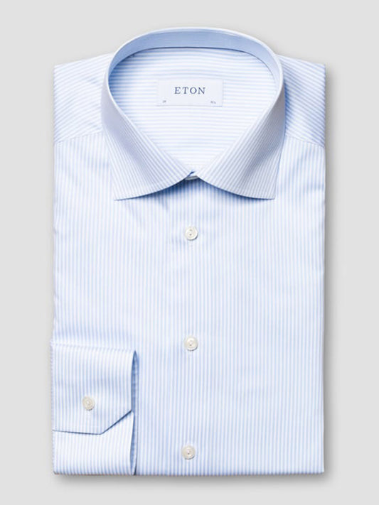 A neatly folded Eton Slim Fit Striped Fine Twill Dress Shirt in light blue with a cut away collar, featuring white bengal stripes and buttoned cuffs, labeled "ETON" on the inside collar.