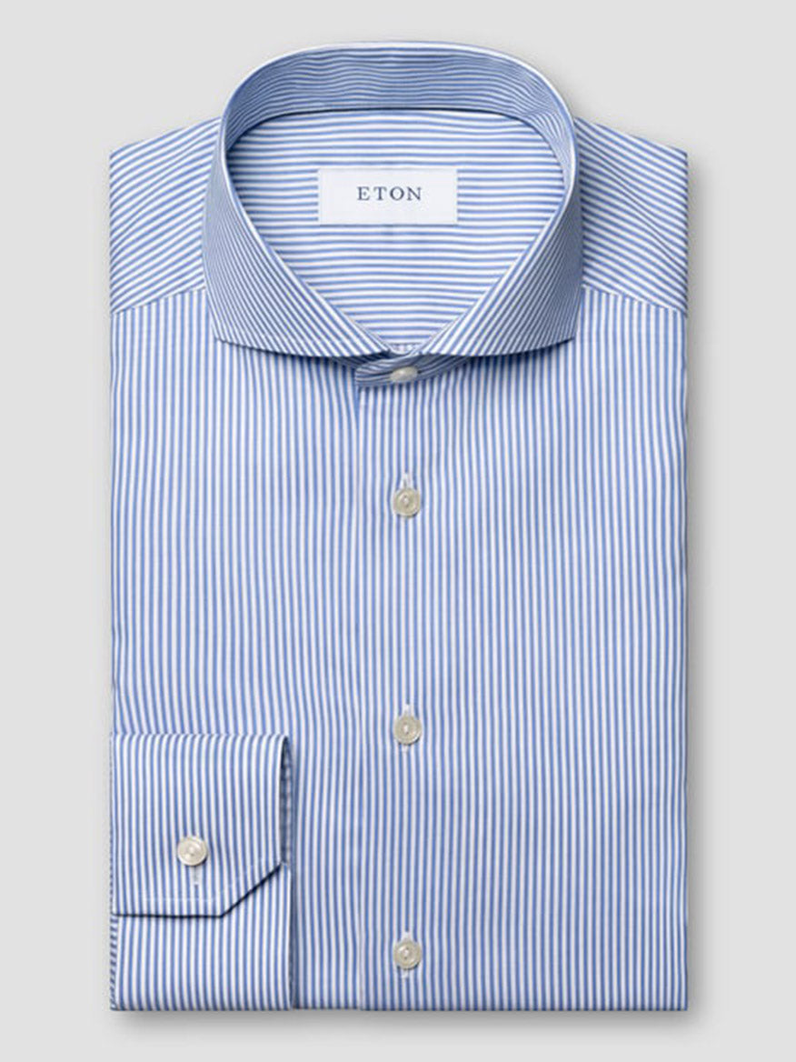 A neatly folded Eton Slim Fit Striped Fine Twill Dress Shirt in mid blue, featuring an extreme cut away collar, long sleeves, white buttons, and classic blue and white bengal stripes.
