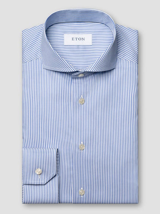 A neatly folded Eton Slim Fit Striped Fine Twill Dress Shirt in mid blue, featuring an extreme cut away collar, long sleeves, white buttons, and classic blue and white bengal stripes.