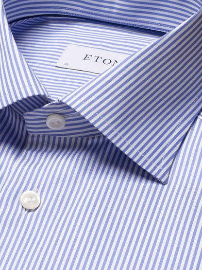 Close-up of an Eton Slim Fit Striped Fine Twill Dress Shirt in Mid Blue, featuring a cut away collar, white buttons, and a visible Eton label inside the collar.