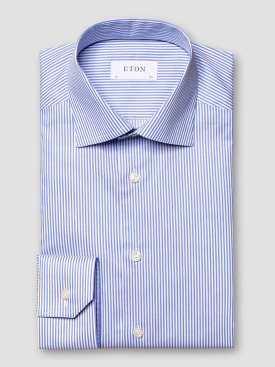 A slim fit, long-sleeved Eton dress shirt in mid blue fine twill with thin white stripes, cut away collar, and white buttons, labeled "ETON" on the inner collar.