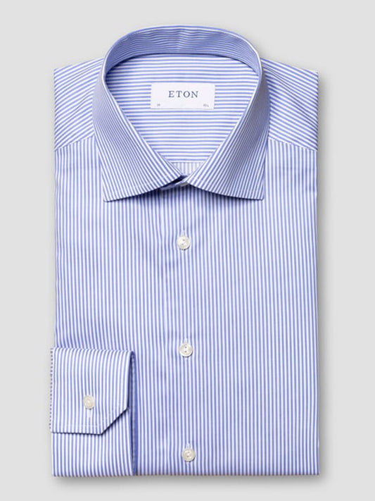 A slim fit, long-sleeved Eton dress shirt in mid blue fine twill with thin white stripes, cut away collar, and white buttons, labeled "ETON" on the inner collar.