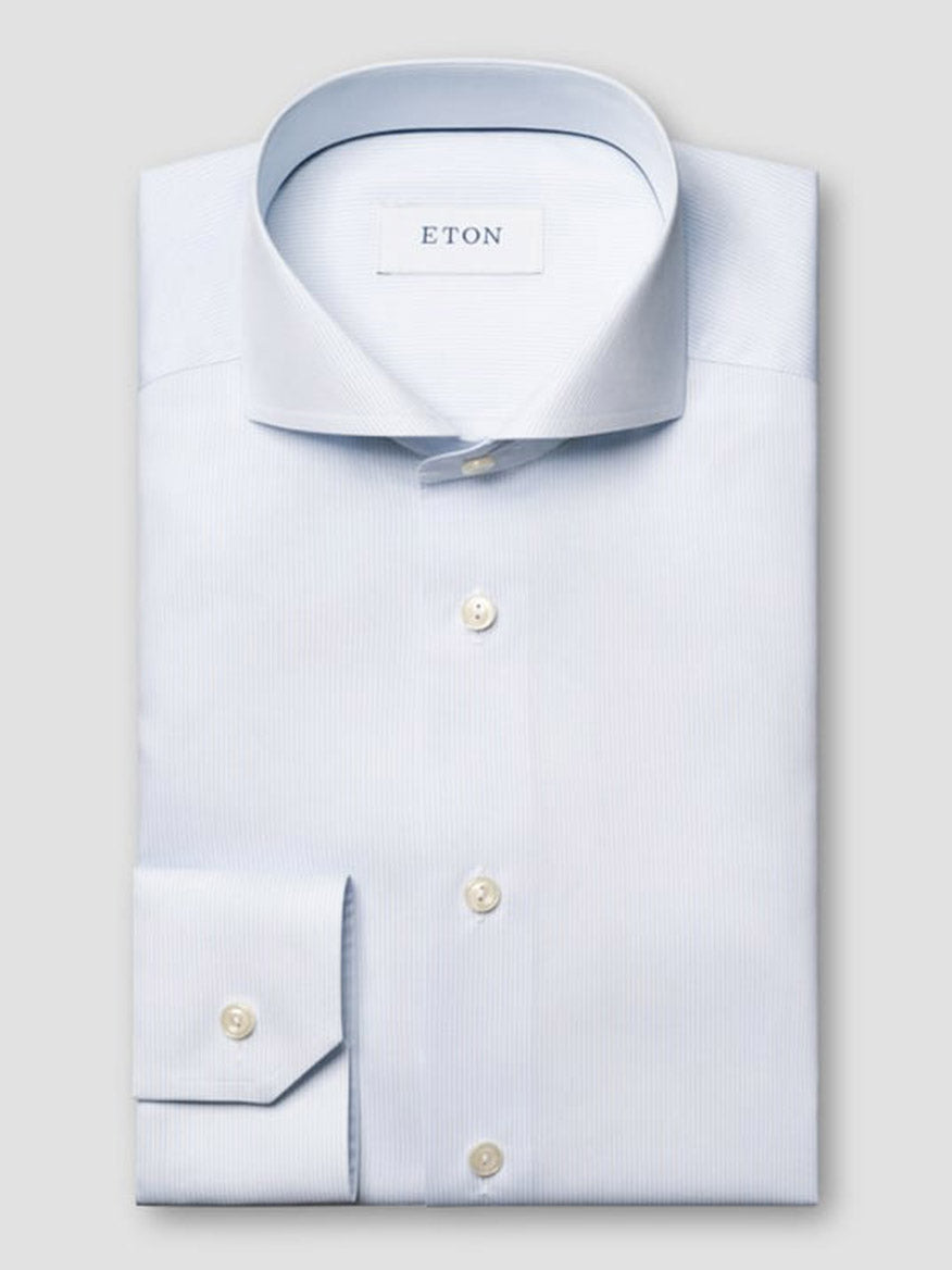 A light blue Eton Slim Fit Striped Twill Dress Shirt is neatly folded, featuring a spread collar, buttoned cuffs, and pearl-colored buttons against a plain background.
