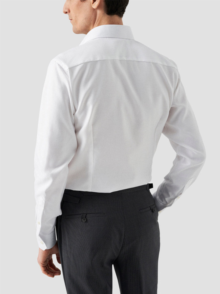 A man is shown from the back wearing an Eton Slim Fit Solid Textured Twill Dress Shirt in White with dark trousers, ideal for business attire, against a plain light background.