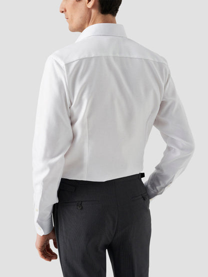 A man is shown from the back wearing an Eton Slim Fit Solid Textured Twill Dress Shirt in White with dark trousers, ideal for business attire, against a plain light background.