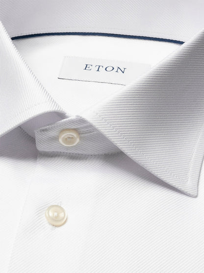 Close-up of the Eton Slim Fit Solid Textured Twill Dress Shirt in White, featuring a pointed collar, pearl buttons, single cuff, and visible brand label—ideal for sharp business attire.