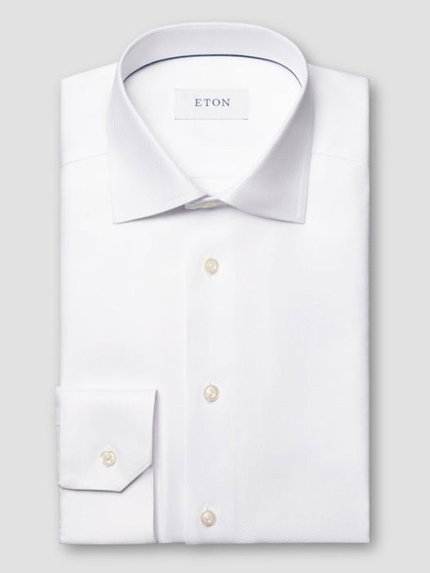 The Eton Slim Fit Solid Textured Twill Dress Shirt in White features a classic collar and single cuff, neatly folded with pearl buttons and displayed against a plain light gray background.