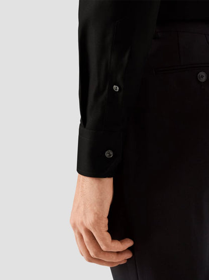 A person shown from the waist down wears the Eton Slim Fit Black Textured Twill Dress Shirt with black pants, highlighting the shirt cuff and hand.