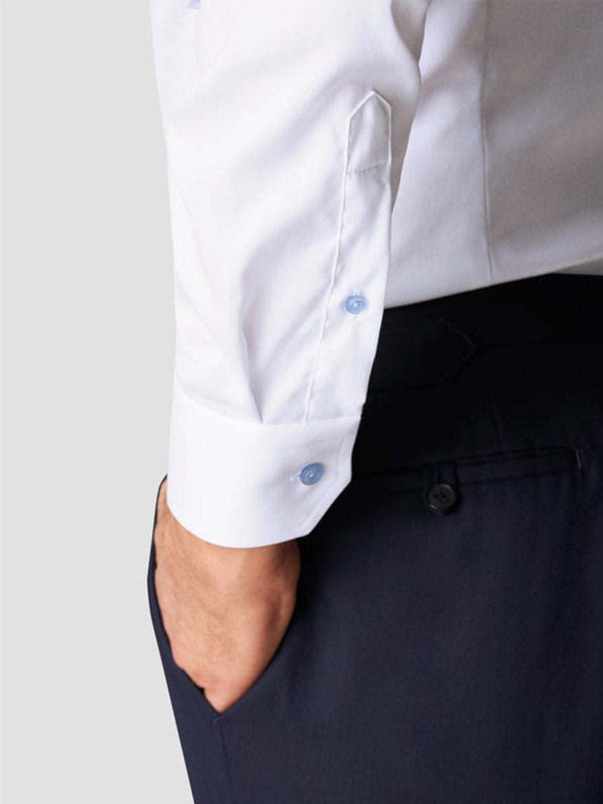 A person shown from the waist down wearing dark trousers and an Eton Slim Fit Signature Twill Dress Shirt in White with Blue Details, styled in a slim fit with one hand in their pocket.