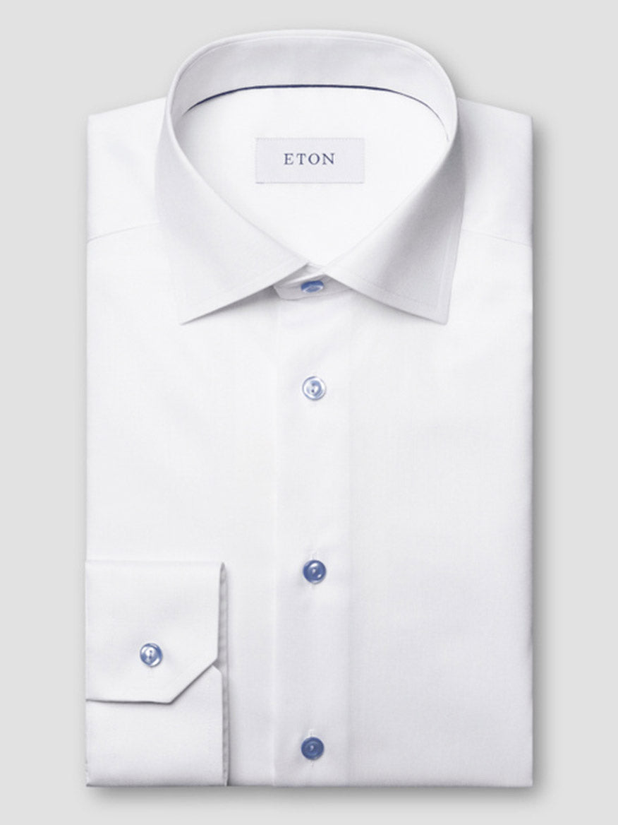 The Eton Slim Fit Signature Twill Dress Shirt in white features blue details, a pointed collar, visible "ETON" label, and wrinkle-resistant fabric, offering classic style with modern functionality.