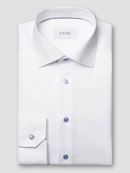 The Eton Slim Fit Signature Twill Dress Shirt in white features blue details, a pointed collar, visible "ETON" label, and wrinkle-resistant fabric, offering classic style with modern functionality.