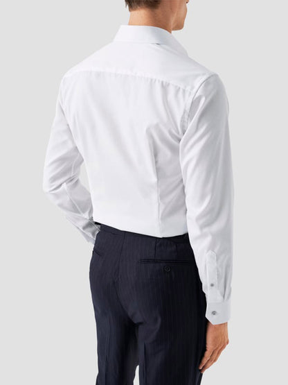 A man is seen from behind wearing the Eton Slim Fit Signature Twill Dress Shirt in white with grey details, paired with dark pinstripe trousers against a plain light gray background.