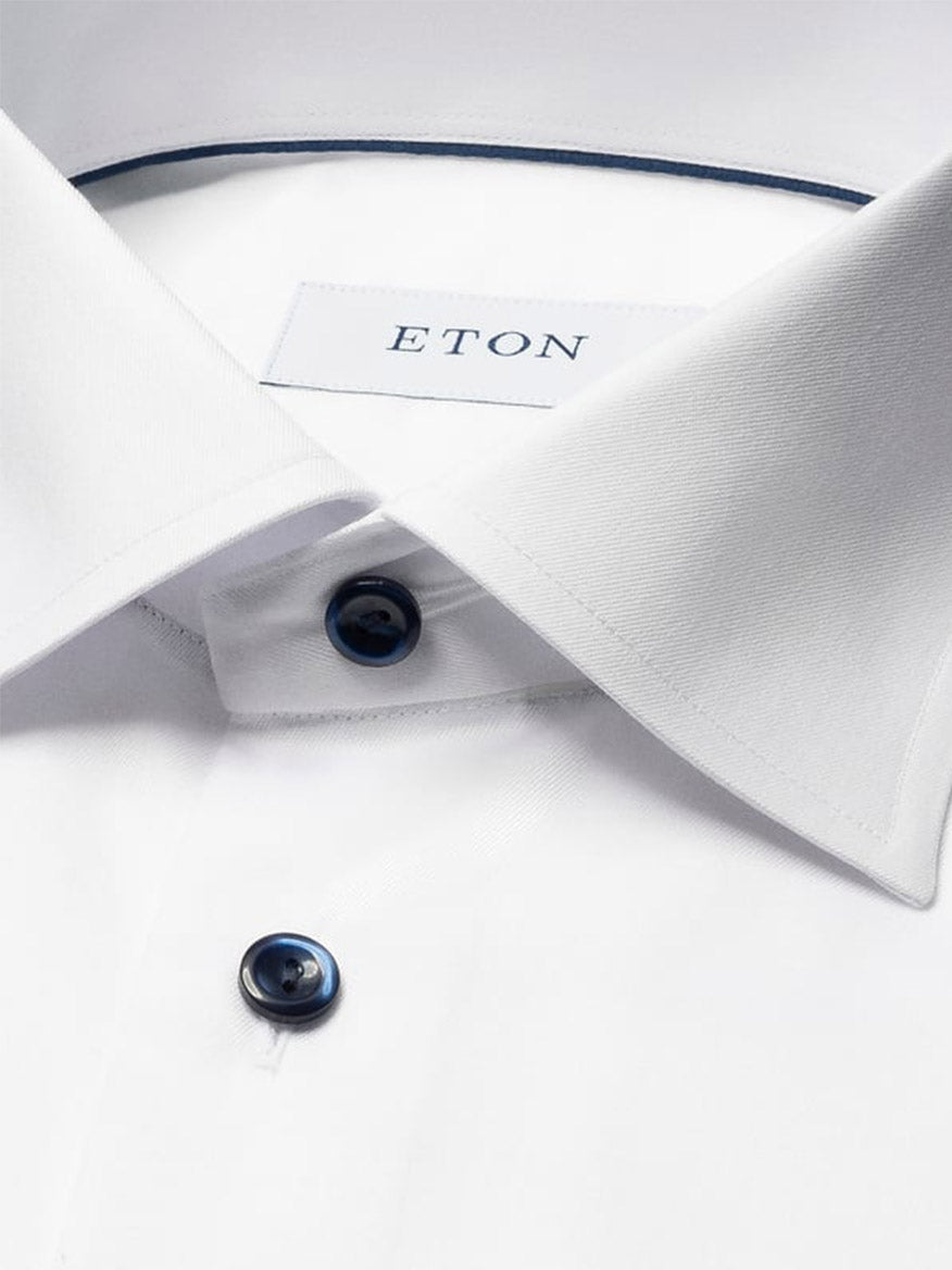 Close-up of the Eton Contemporary Fit Solid Signature Twill Dress Shirt in white, featuring navy details, blue buttons, and a label inside the collar.