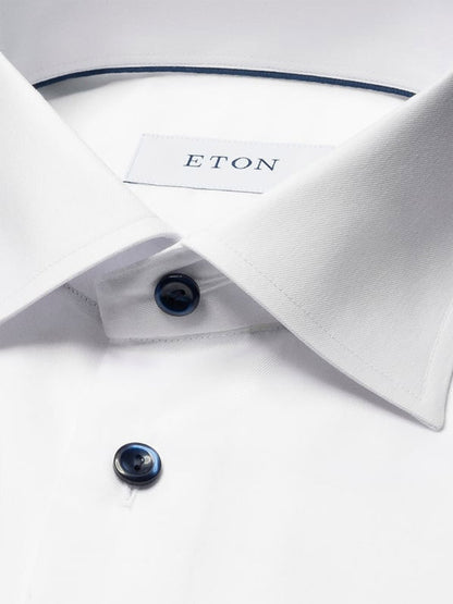 Close-up of the Eton Slim Fit Solid Signature Twill Dress Shirt in white, featuring navy details, dark buttons, and an "ETON" label inside the collar.
