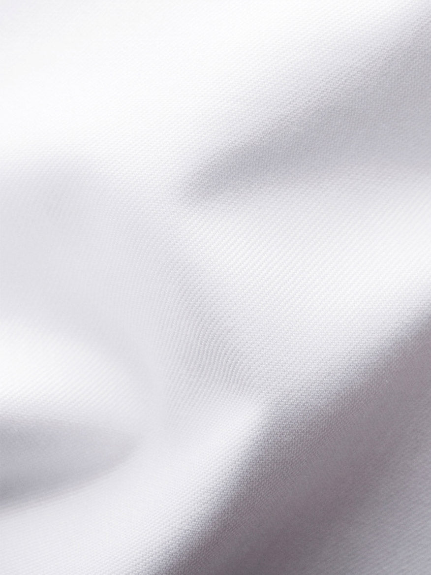 Close-up of the Eton Slim Fit Solid Signature Twill Dress Shirt in white with navy details, highlighting its textured organic cotton fabric and soft folds.