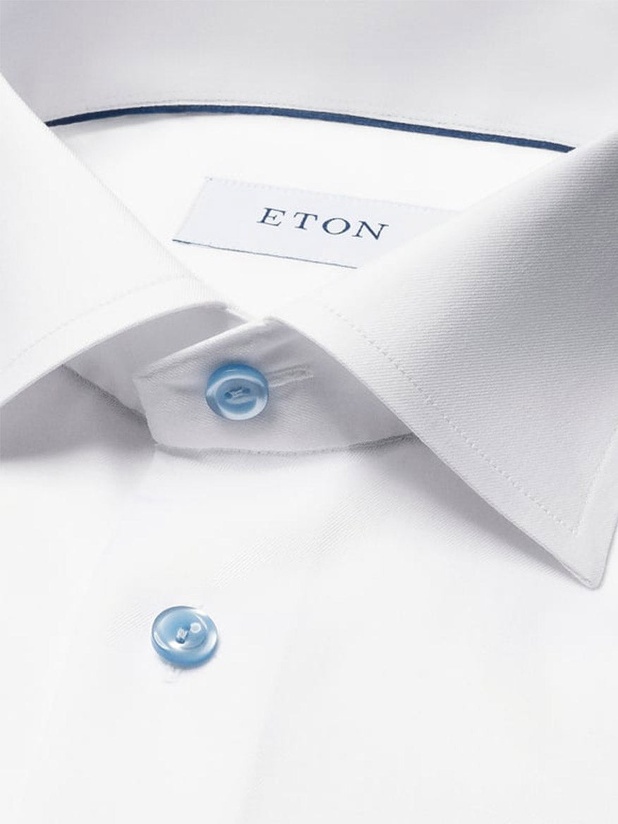 Close-up of the Eton Contemporary Fit White Twill Dress Shirt With Blue Details, showcasing light blue buttons and a visible brand label inside the collar.