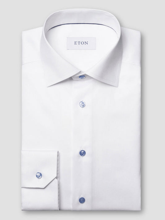 The Eton Contemporary Fit White Twill Dress Shirt with blue details features a spread collar and is neatly folded, displayed on a plain light gray background.