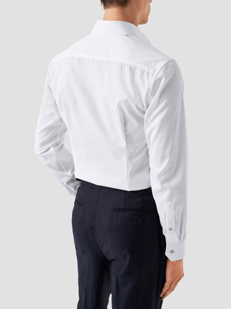 A man shown from the back against a plain light background wears an Eton Contemporary Fit White Twill Dress Shirt With Grey Details and dark pinstripe trousers.