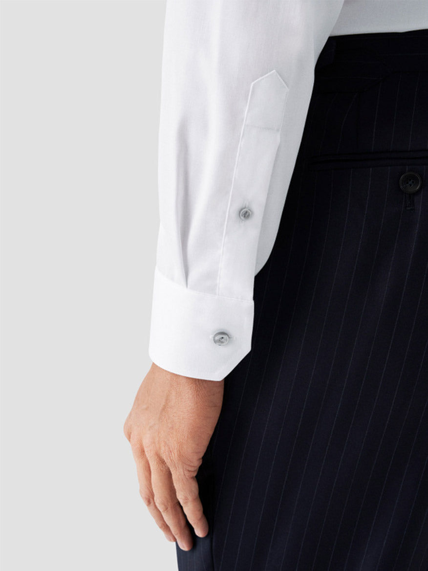 A person wearing an Eton Contemporary Fit White Twill Dress Shirt with grey details and dark pinstripe trousers, showing their hand by their side.