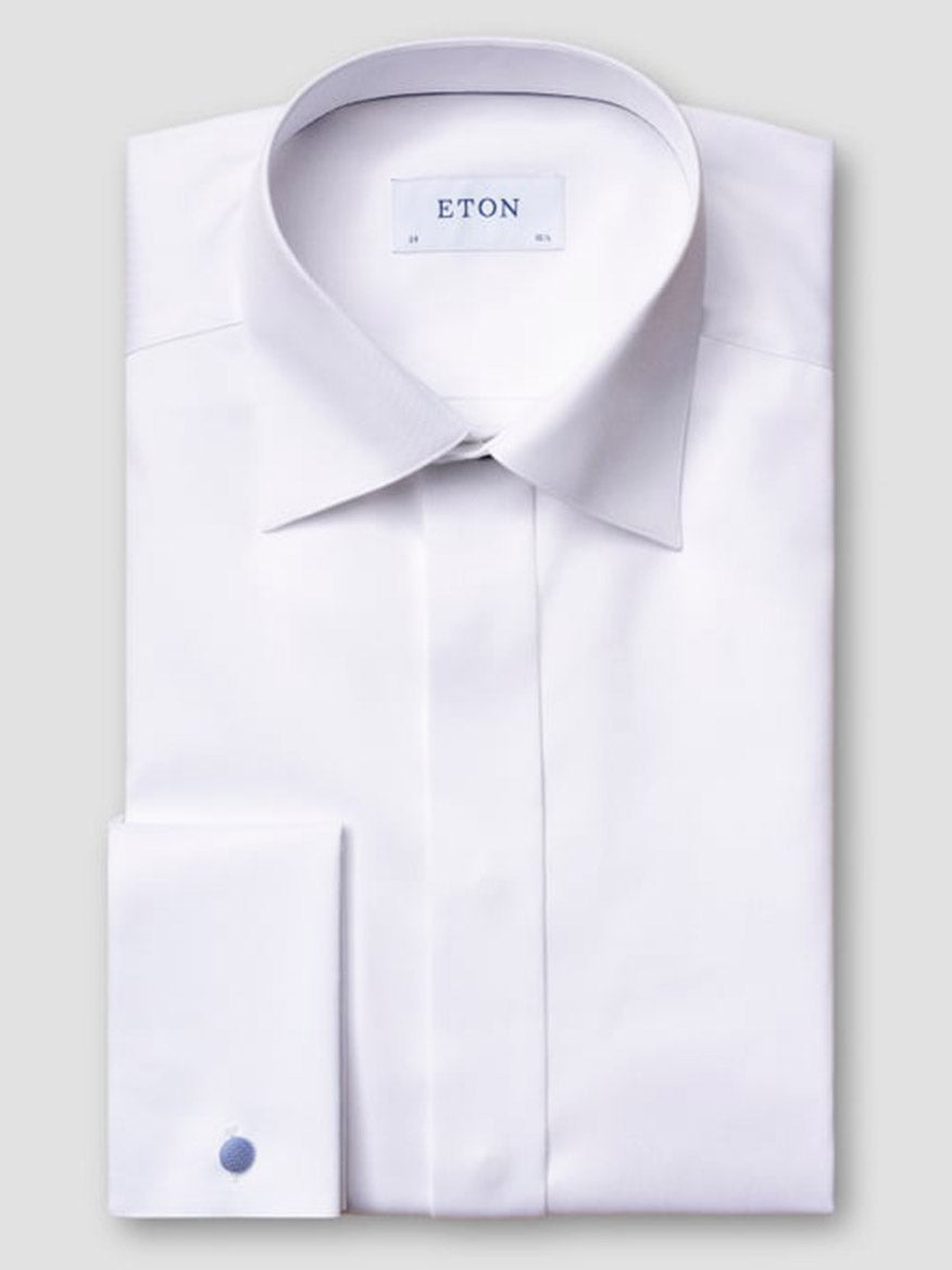 The Eton Slim Fit Fly Front Signature Twill Evening Shirt in White, made from organic cotton with a classic collar and French cuffs, features a single blue cufflink and inner "ETON" label—ideal for any black-tie event.
