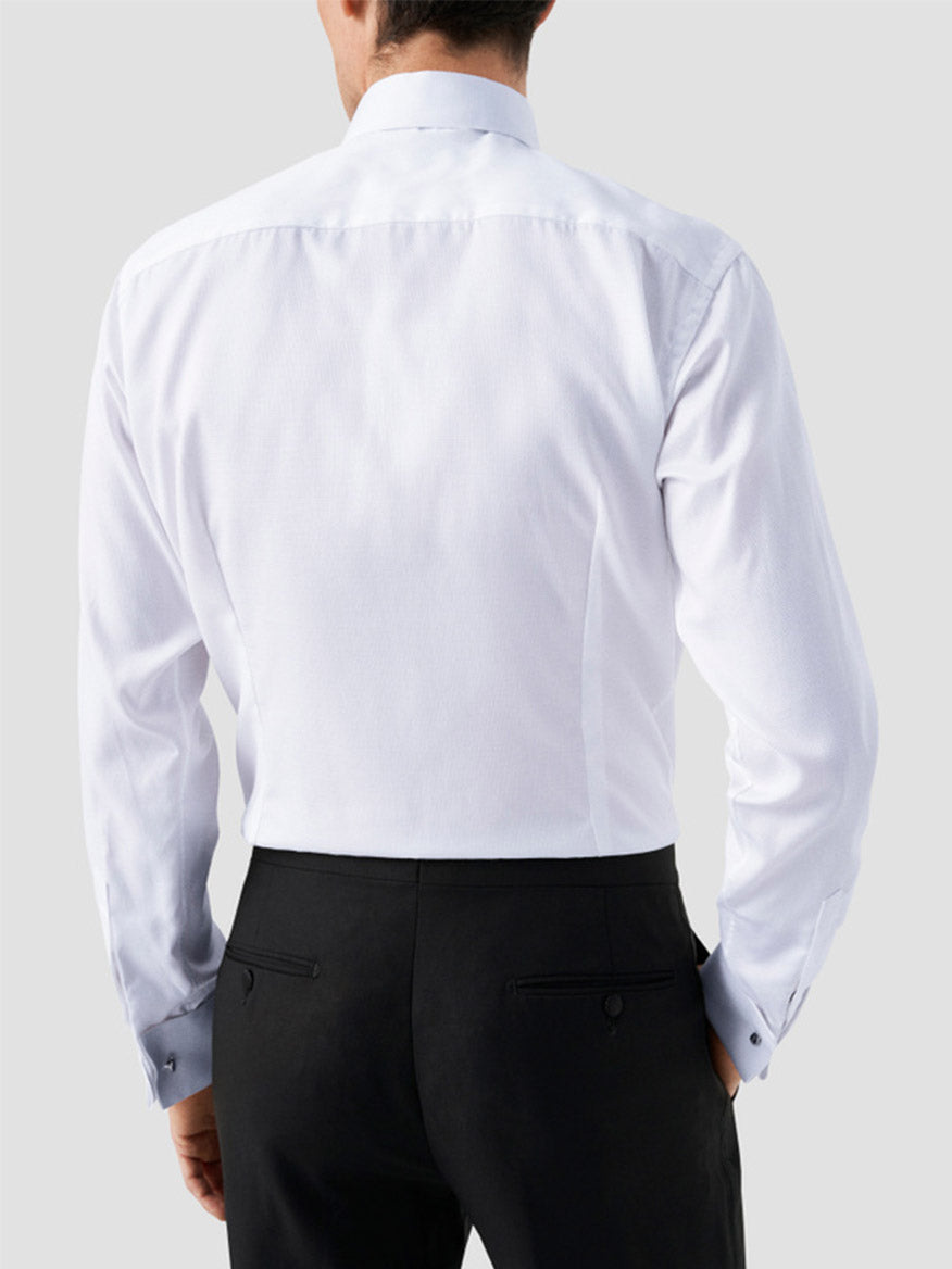 A man is shown from the back against a plain light gray background wearing an Eton Contemporary Fit White Dobby Formal Shirt with French cuffs and black dress pants.