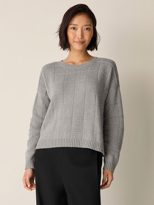 A woman with short dark hair wears the Eileen Fisher Cotton & Recycled Cashmere Crew Neck Top in Dark Pearl and black pants, standing against a plain light background.