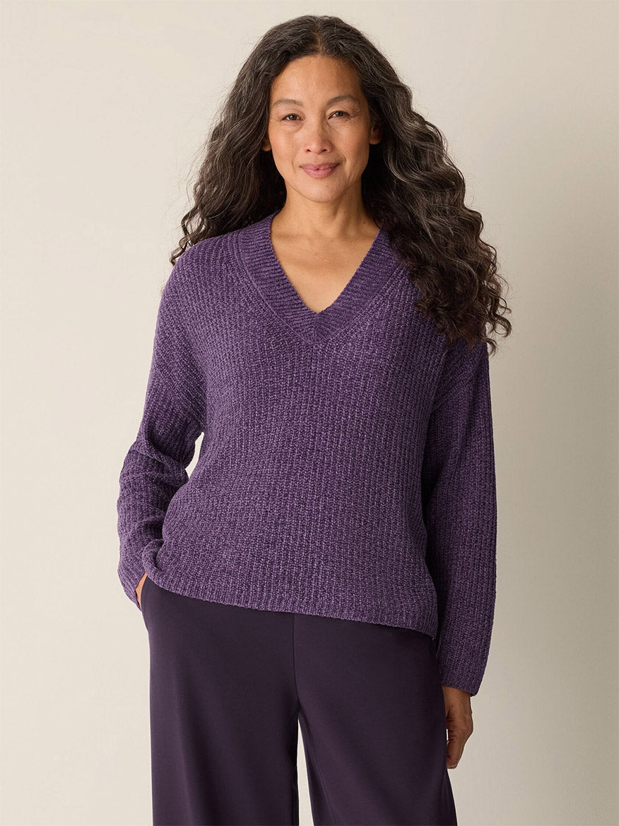 A woman with long hair is wearing the Eileen Fisher Chenille Blend V-Neck Top in Mulled Grape and matching pants.