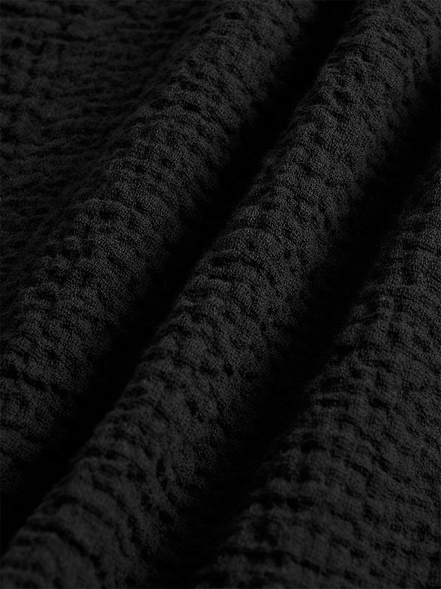 Close-up of the Eileen Fisher Organic Cotton Doubleweave Classic Collar Jacket in Black, showing the organic cotton fabric’s textured waffle-like weave and visible folds—ideal for a boxy, structured look.