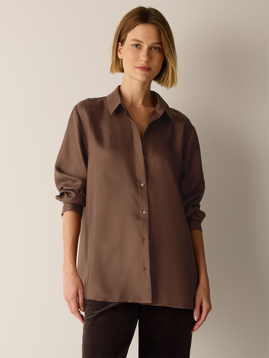 A person wearing an Eileen Fisher Silk Twill Classic Collar Shirt in Hazelwood, a long-sleeved, brown, Fair Trade Certified button-down with a classic collar.