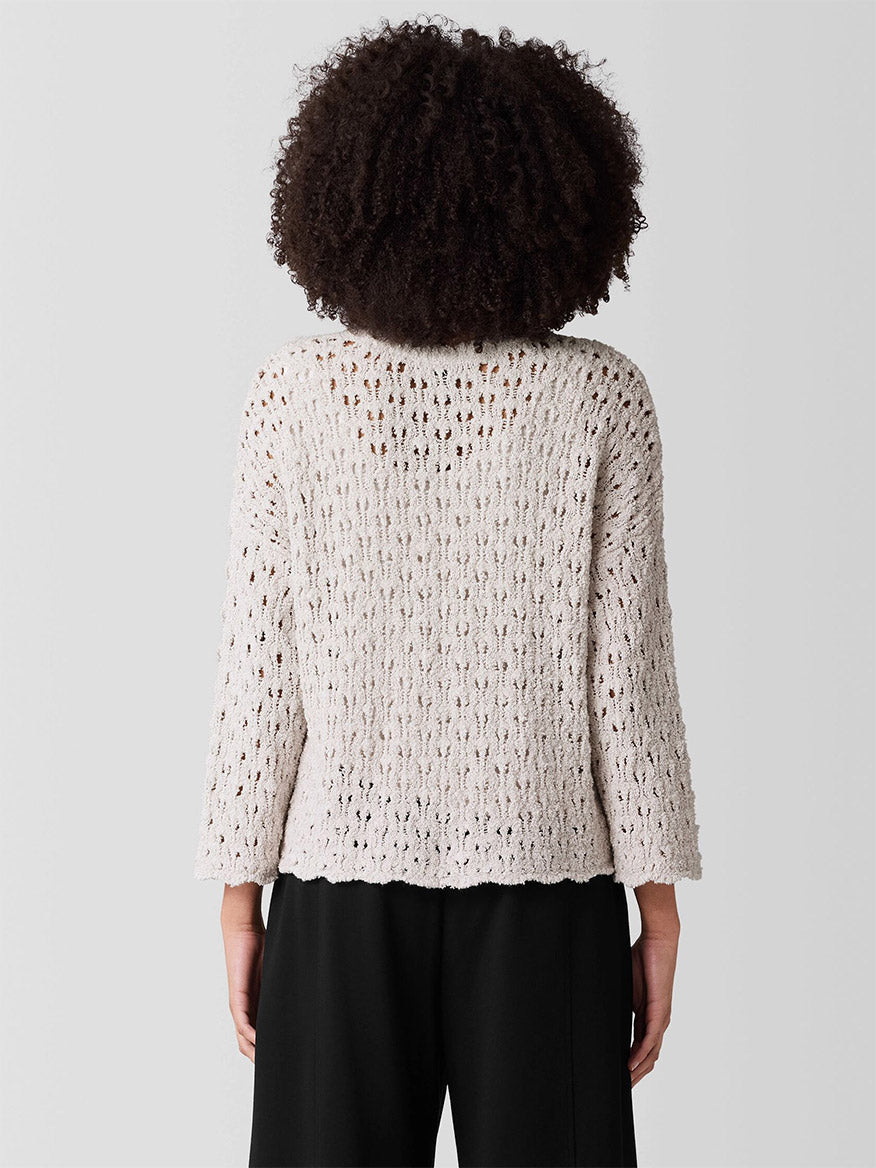 Person with curly hair facing away, wearing the Eileen Fisher Cotton Fluff Bracelet Sleeve Top in Bone and black pants against a plain gray background.