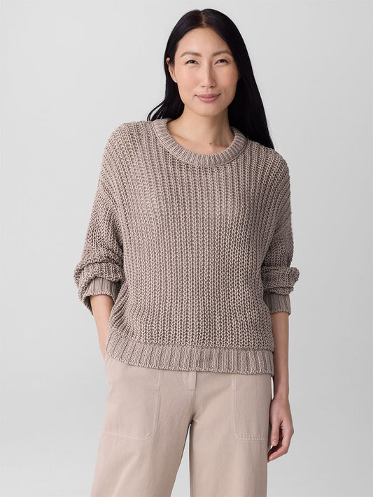 A person with long dark hair wears the Eileen Fisher Peruvian Organic Cotton Cord Crew Neck Top in Wheat and light beige pants, standing against a plain, light background.