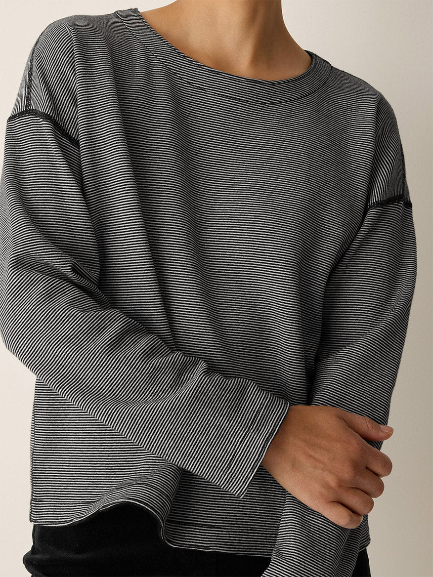Person wearing the Eileen Fisher Doubleknit Organic Cotton Stripe Reversible Top in Black/Ivory, featuring a loose, boxy fit and long sleeves, with arms crossed in front.