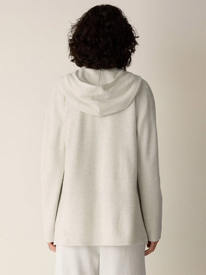 Back view of a person wearing an Eileen Fisher Fine Felted Wool Hooded Cardigan in Regenerative Wool in Plaster, a long-sleeved, off-white hooded cardigan made of fine wool.