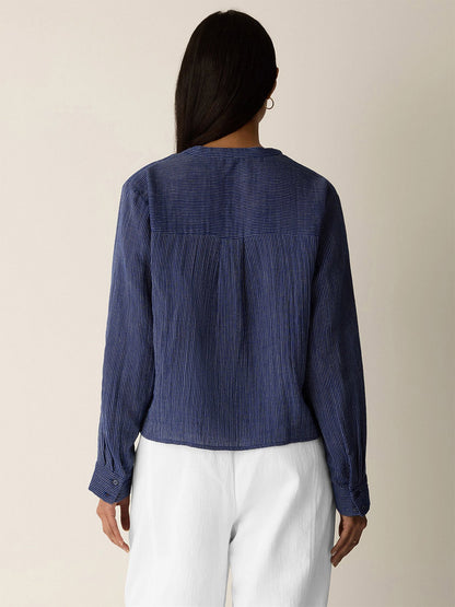 A person with long dark hair wears the Eileen Fisher Striped Organic Cotton Gauze Band Collar Shirt in Deep Dive, shown from the back against a plain background.