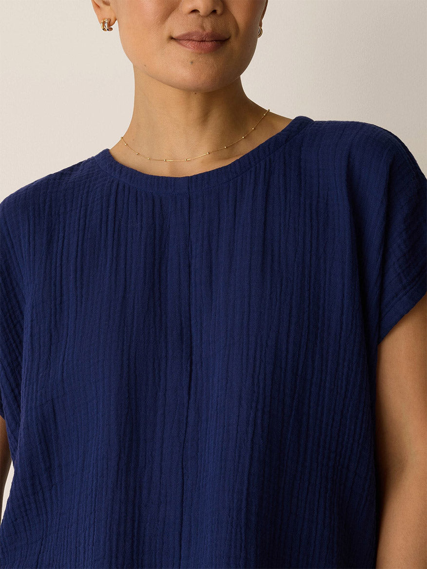 A person wears the Eileen Fisher Organic Cotton Lofty Gauze Round Neck Box-Top in Deep Dive with a thin gold necklace, shown from shoulders to mouth against a plain background.